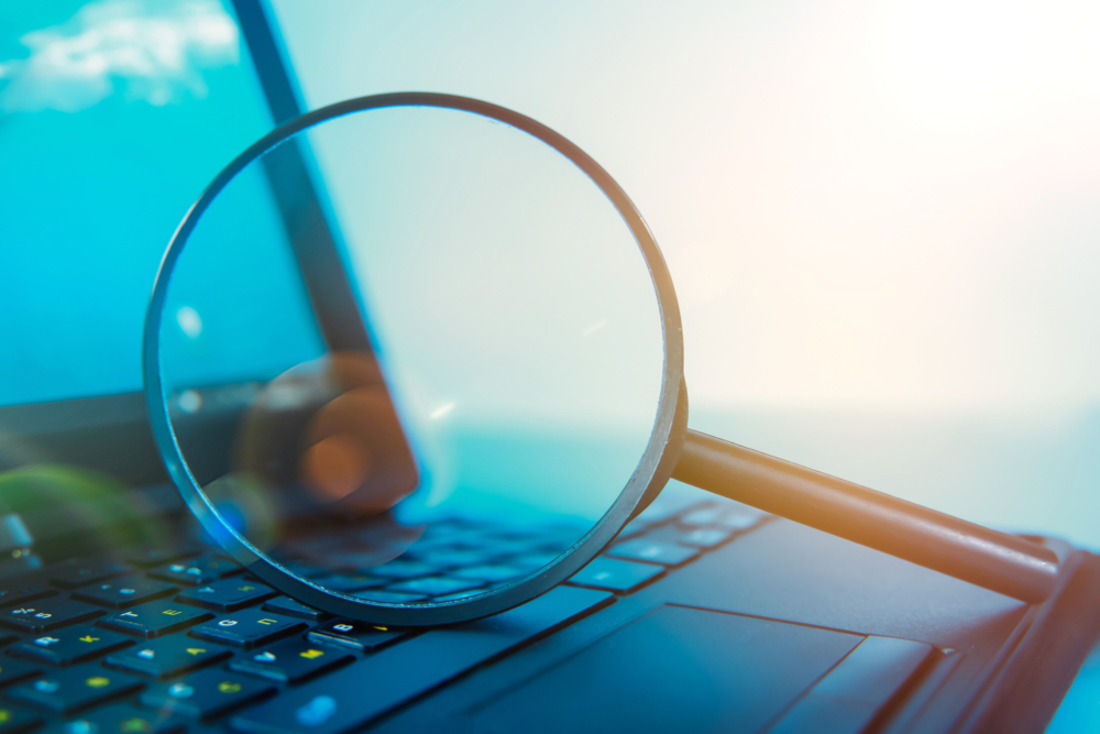 A magnifying glass resting on a laptop keyboard