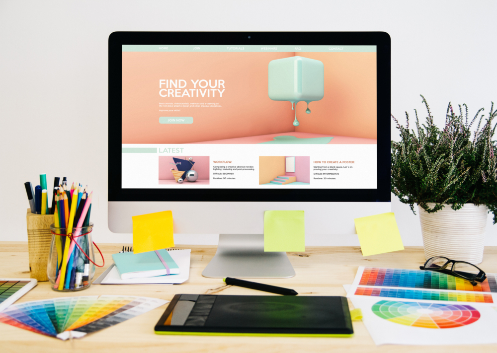 Colourful brand assets and a monitor showing website design