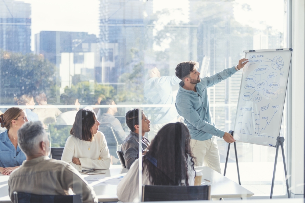 Staff looking at a whiteboard in a sunny office