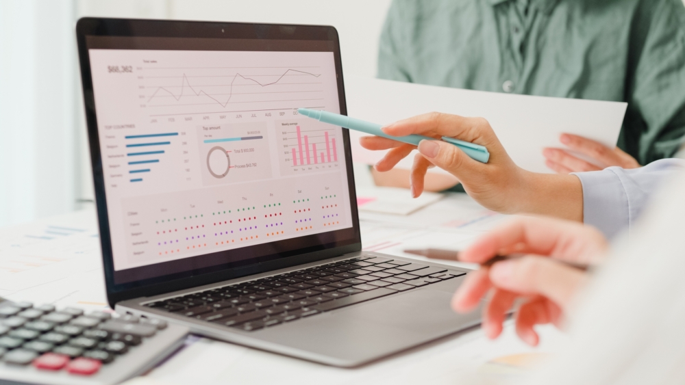 Hands gesturing at a laptop with analytics onscreen