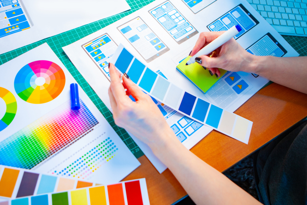 Hands on a desk with colour palettes and UI designs