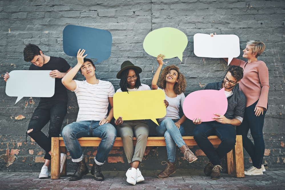 Diverse people hold up blank speech bubbles in different colours and sizes