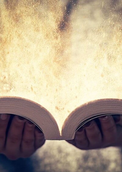 Hands holding an open book that emanates light