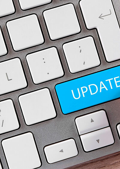 A keyboard with someone's finger hovering over the word UPDATE