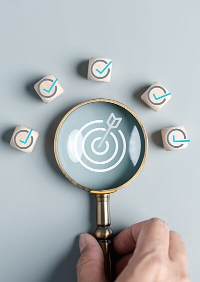 A magnifying glass with a bullseye and arrow in the centre, surrounded by tick icons.