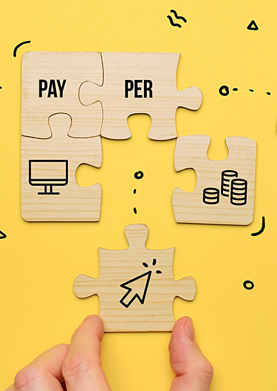 Hands putting together puzzle pieces that say "pay-per-click"