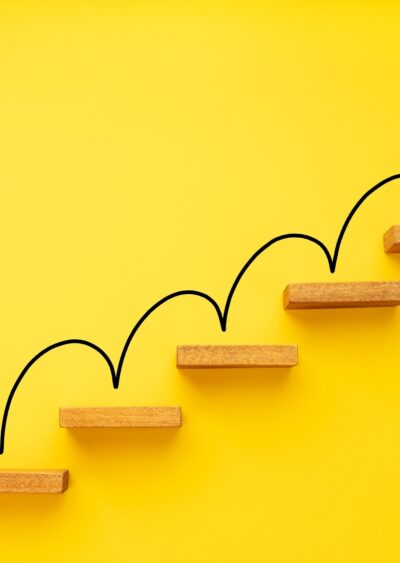 An arrow climbing stairs on a yellow background.