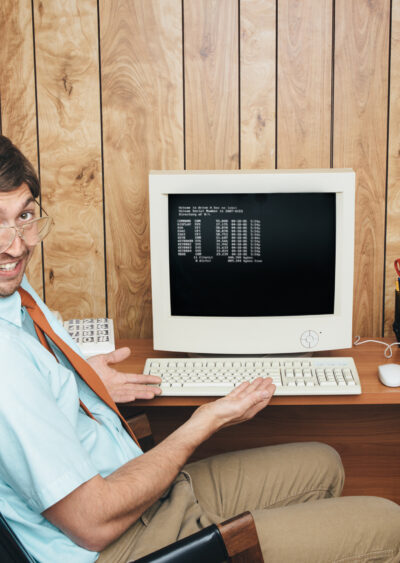 Man at old computer with glasses leaning back