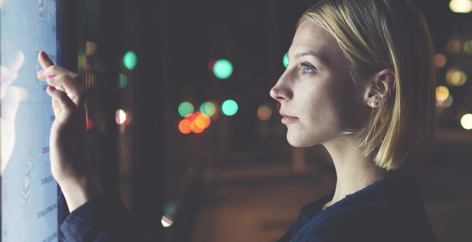 Woman touching a screen at night