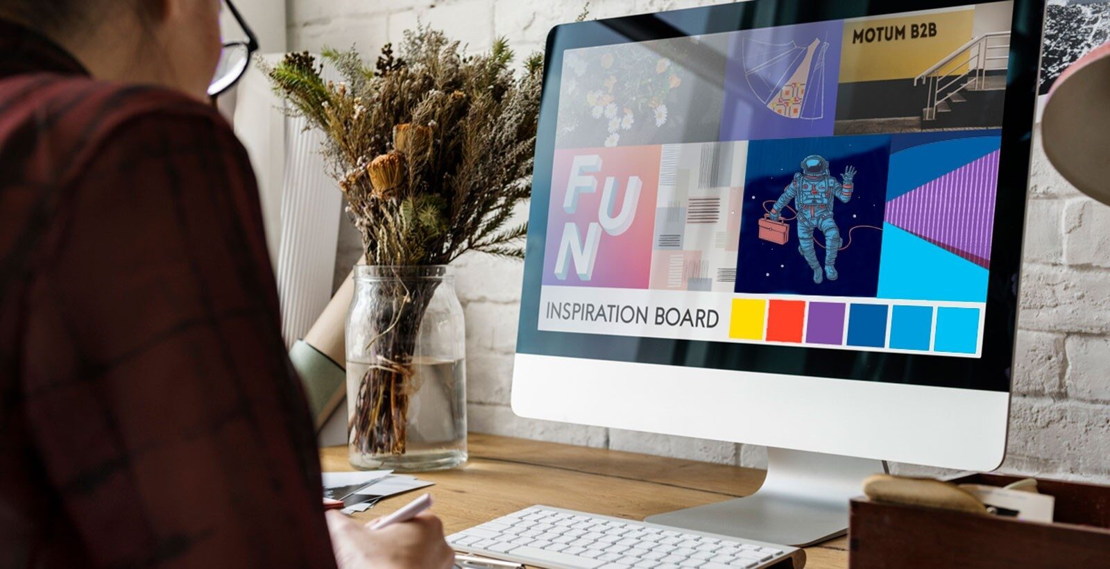 A woman facing a computer monitor with a colourful mood board onscreen