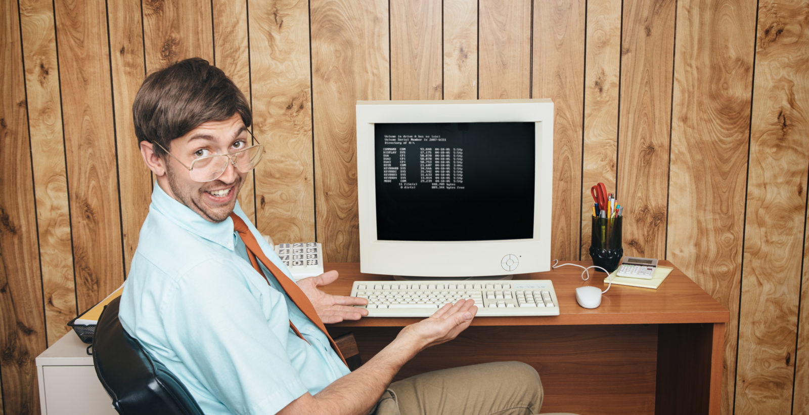 Man at old computer with glasses leaning back