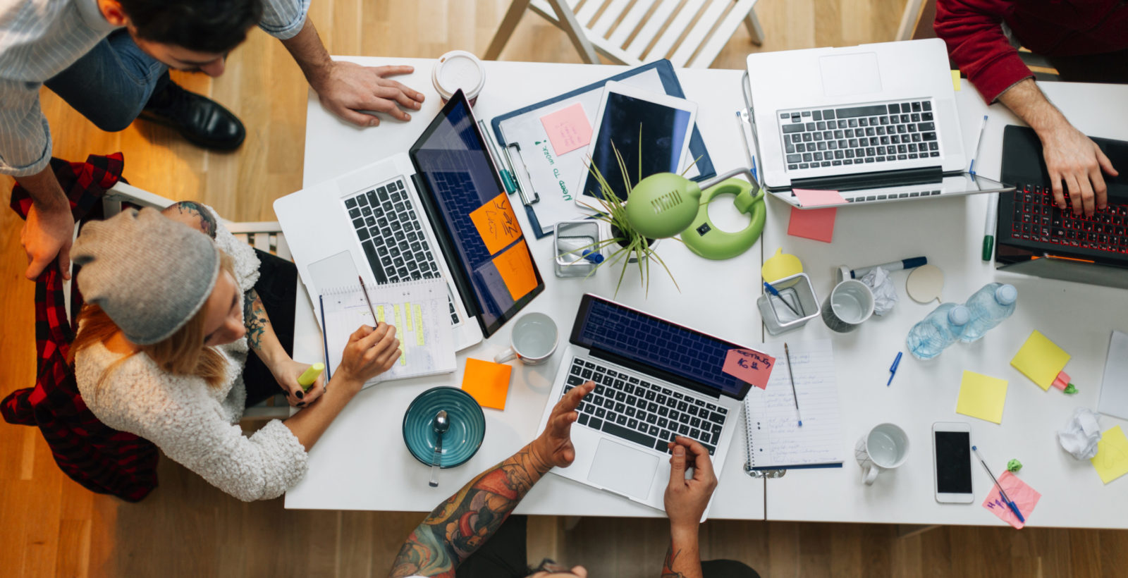 Overhead view of marketing team working at a desk with laptops